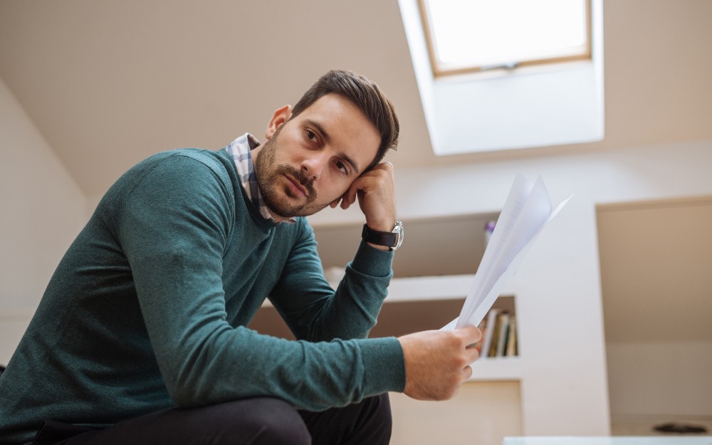 Pensive man holding documents, thinking about why his TPD claim was denied