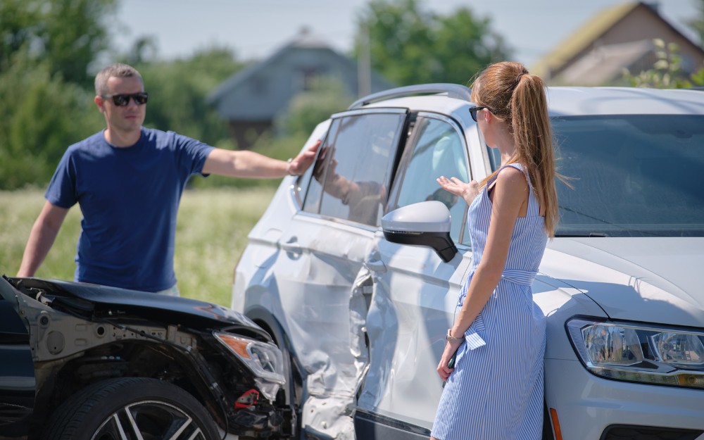 Male and female drivers talking about partial fault in a car accident; drivers partly at fault