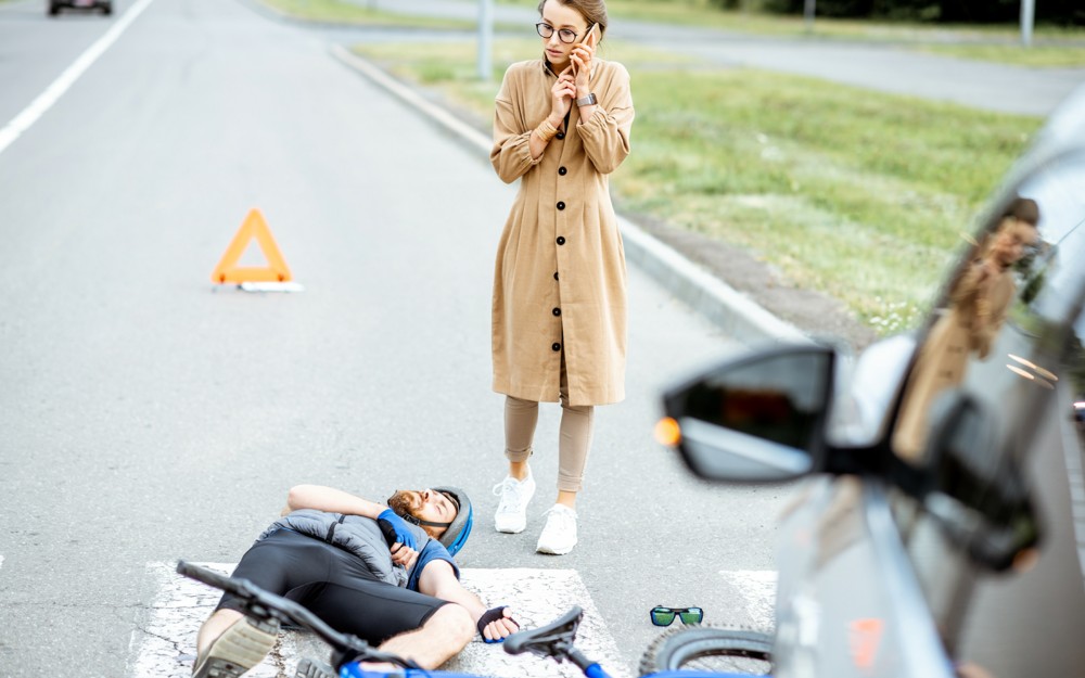 man on the road after bicycle accidents, woman is calling emergency services