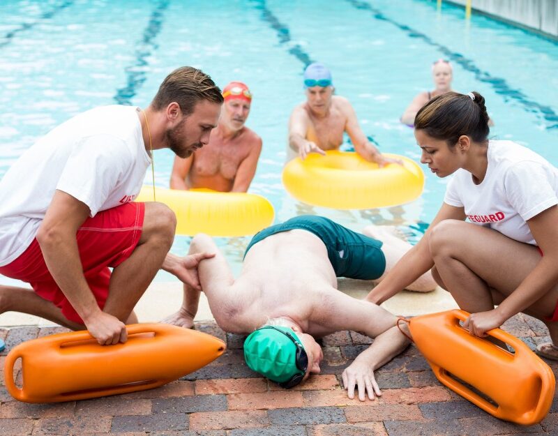 Man helped by lifeguards after swimming pool injuries