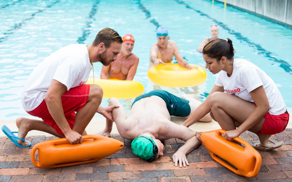 Man helped by lifeguards after swimming pool injuries