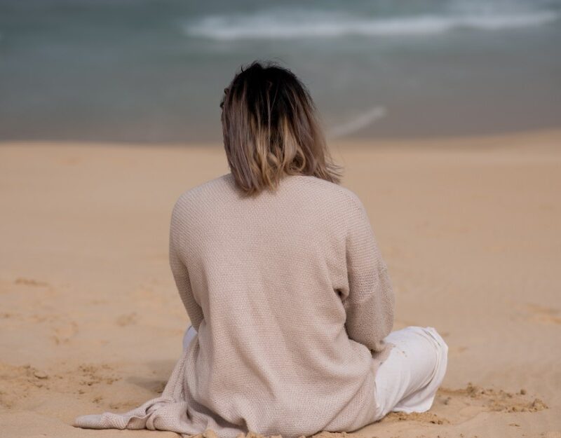 Woman whose back turned sits at the bakh, contemplating about compensation for experiencing institutional abuse in Australian religious settings