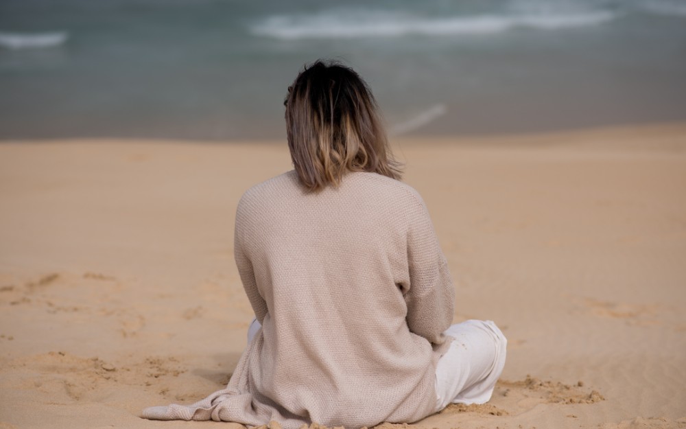 Woman whose back turned sits at the bakh, contemplating about compensation for experiencing institutional abuse in Australian religious settings